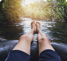 Man&#39;s legs on inflatable device going down a river